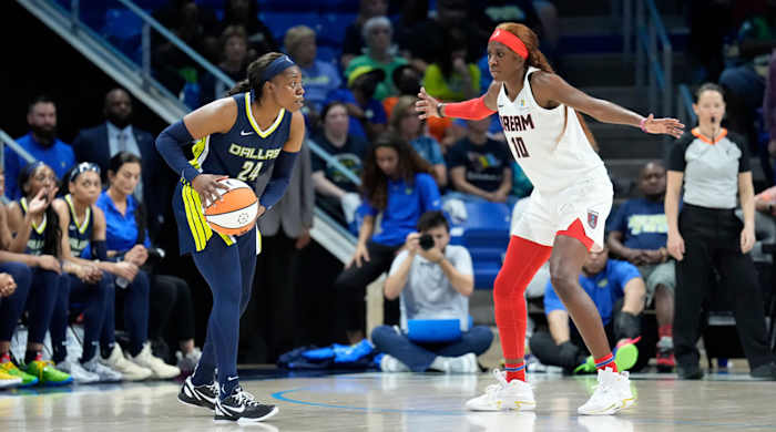 Wings guard Arike Ogunbowale tries to dribble past Atlanta's Rhyne Howard.